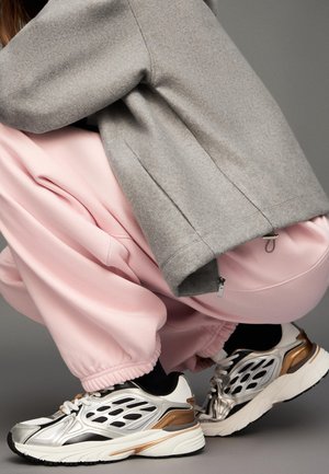 Light gray fleece sweatshirt with a zippered hem, paired with loose pink sweatpants. Features silver and gold accented running shoes.