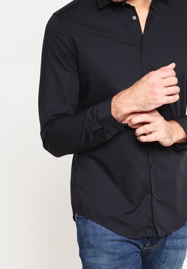Black long-sleeve shirt with a button-down collar and smooth texture. Features a fitted design and subtle front buttons. Worn with denim.