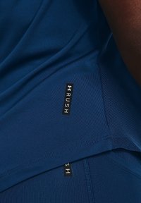 Granatowa koszulka sportowa z gładkiego materiału, z siateczkową wstawką, z czarnymi metkami "RUSH" oraz kontrastowymi detalami w szyciu.