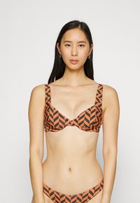 Set di reggiseno e bikini con motivo a zigzag in arancione e nero. Il reggiseno presenta spalline larghe e un design con stecche. Tessuto morbido e liscio.