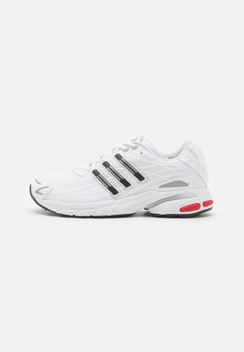 Weiße Sportlicher Schuh mit schwarzen Streifen, strukturiertem Obermaterial, gepolstertem Kragen und roten Akzenten an der Sohle. Leicht und mit geschwungenem Design.