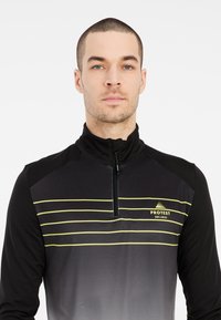 Zwarte sportieve pullover met een halve rits nek, met horizontale gele strepen op de borst en een verloopontwerp op de achterkant.
