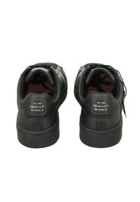 Schwarze Sneakers mit Obermaterial aus Leder und Textil, gepolstertem Kragen, Label an der Ferse, flacher Gummisohle und Schnürdetails.