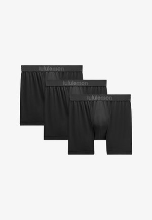 Tres bóxers de malla negros de Lululemon con cintura con marca, dispuestos uno al lado del otro sobre un fondo blanco.