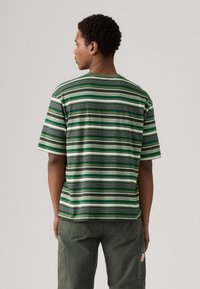 Camisa de manga corta a rayas verdes y blancas con un corte relajado, hecha de una tela suave, que presenta un cuello redondo clásico y sin logotipos visibles.