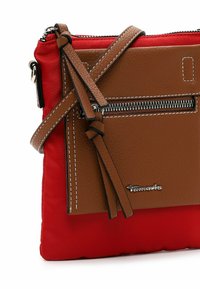 Brown leather and red nylon crossbody bag with a zippered pouch, decorative tassels, and white stitching. Features a silver logo accent.