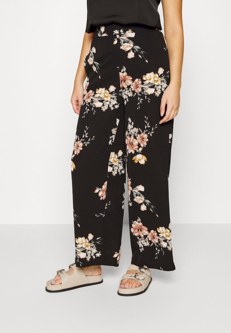 Pantalons larges noirs avec un motif floral dans des tons de rose, jaune et blanc. Fabriqués en matériau léger, dotés de poches latérales.