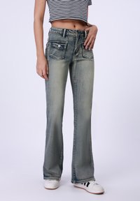 Flared jeans in lichtblauwe denim met een vervaagde afwerking. Kenmerken zijn onder andere vijf zakken, een knoopsluiting en een minimalistisch ontwerp.