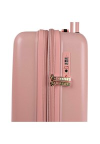 Maleta rígida rosa con acabado texturizado, cierre de doble cremallera, candado de combinación y acentos en tono dorado. Diseño compacto y aerodinámico.