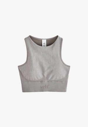 Sutien sport gri și colanți cu talie înaltă din material neted și elastic. Tenisi maronii cu accente albe completează ținuta.