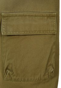 Olivgrünes Stofftasche mit Klappe und sichtbaren Nähten. Texturierte Oberfläche und seitliche Einklappung erhöhen Funktionalität und Design.