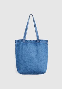 Τσάντα tote από μπλε τζιν με δύο μακριές λαβές, επίπεδο πάτο και χωρίς εμφανή λογότυπα ή διακοσμητικά στοιχεία, εμφανιζόμενη σε απλό λευκό φόντο.