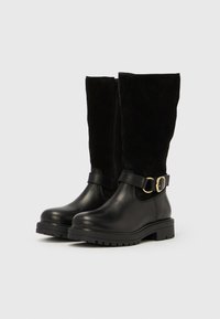 Črni škornji do sredine meč z zgornjim delom iz semiša, spodnjim iz usnja, stranskim zadrgo, debelim podplatom in okrasnim zlatim trakom z zaponko okoli gležnja.