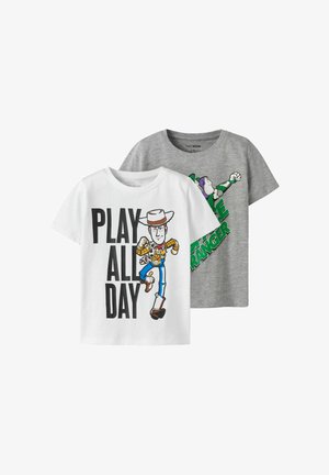 Två t-shirts med kort ärm: en vit med en tryckt grafik av en cowboy och texten "LEK HELA DAGEN", och en grå med en grön och lila rymdpatrull.