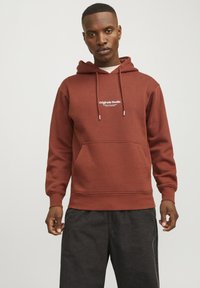 Felpa con cappuccio marrone, con tasca frontale e testo del logo bianco. Realizzata in tessuto morbido, presenta lacci e polsini a coste.