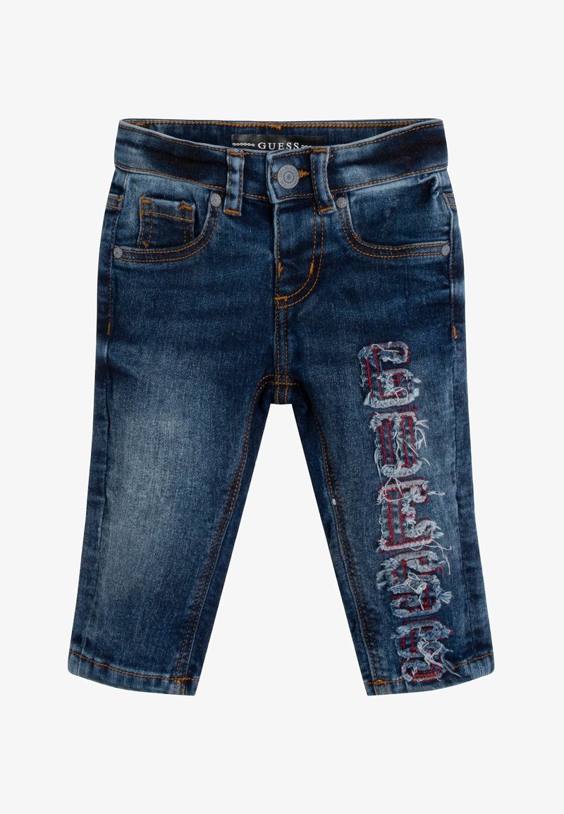 Vaqueros de mezclilla en azul oscuro con un acabado desgastado y letras bordadas en rojo en la pierna izquierda. Presentan un diseño clásico de cinco bolsillos.