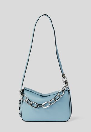 Sac à main bleu clair avec une fine bandoulière et un gros détail en chaîne argentée à l'avant sur fond uni.