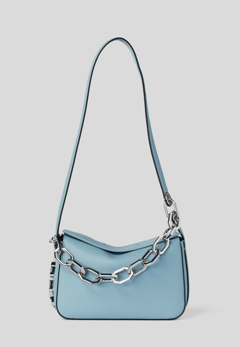 Sac à main bleu clair avec une fine bandoulière et un gros détail en chaîne argentée à l'avant sur fond uni.