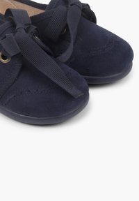 Scarpe in suede blu navy con punta arrotondata, cuciture decorative e lacci in nylon piatti. Presentano occhielli in metallo e suola in gomma.
