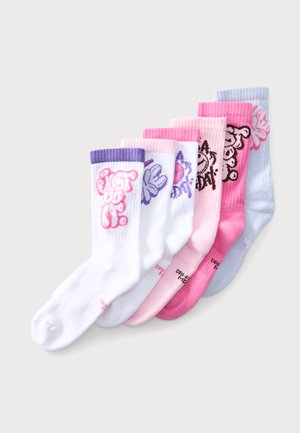 Six paires de chaussettes montantes colorées en blanc, rose, magenta et bleu clair avec différents motifs graphiques et bordures côtelées sont alignées côte à côte.