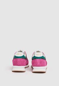 Paire de baskets roses, vertes et blanches vues de dos, avec « 1973 » imprimé en or sur les languettes de talon.