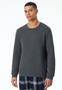 Gequilte grijze sweatshirt met ronde hals, lange mouwen en textuurpatroon; gedragen over blauwe geruite broek.