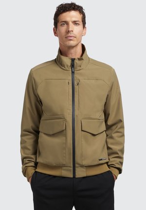Brown, zip-up jacket with a high collar, two chest pockets, and textured cuffs. Smooth fabric with a minimalist design and no visible logos.