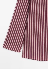 Košile s dlouhým rukávem s vertikálními pruhy v barvách burgundská červeň a béžová, zobrazující část rukávu a trupu na bílém pozadí.