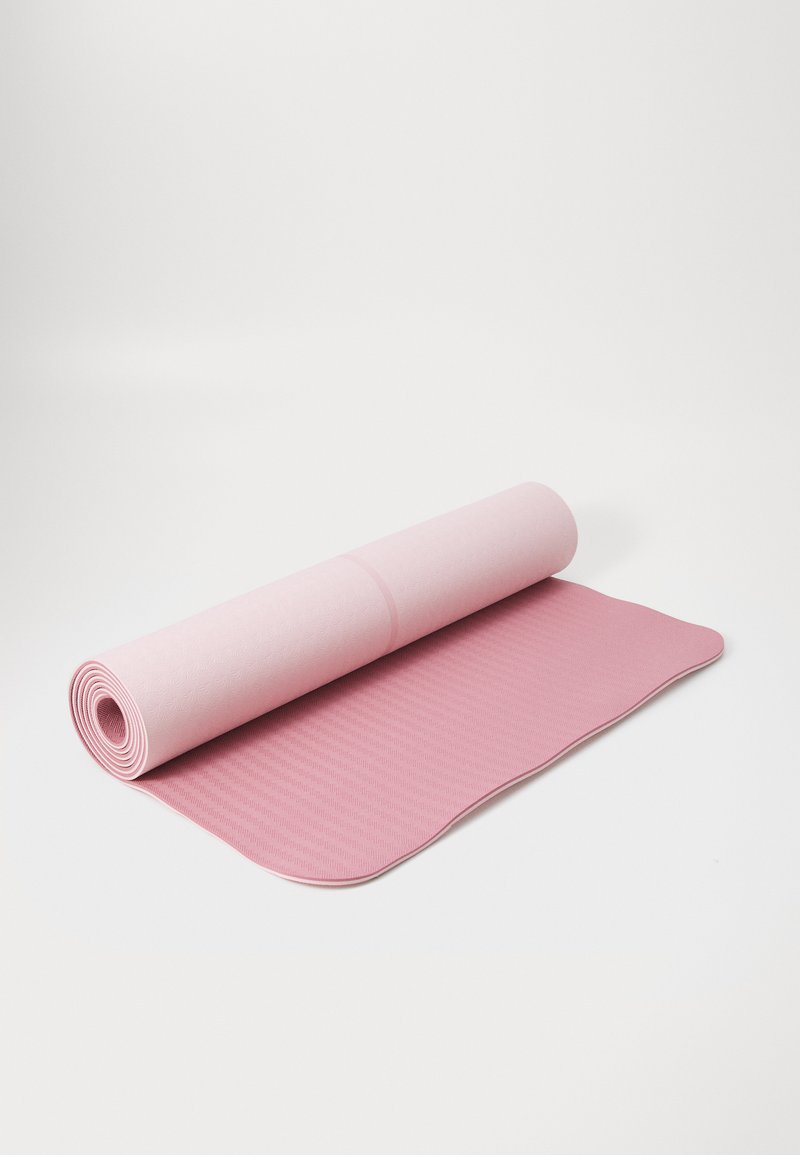 Tapis de yoga rose déroulé à moitié, fabriqué en matériau texturé avec un bord ondulé et un motif léger. Surface lisse idéale pour le yoga ou l'exercice.