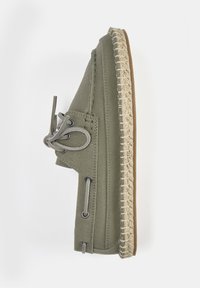 Bateau en toile verte avec une semelle en espadrille, présentant une bordure en jute tissé, des œillets en métal et un détail de lacet assorti sur le c ôté.