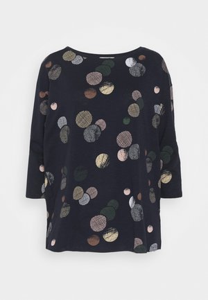 Chemise à manches longues bleu marine avec des motifs circulaires multicolores dispersés sur le devant et les manches.