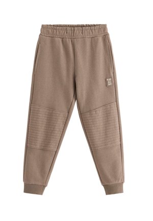 Brune joggebukser med elastisk talje, ribstrikkede manchetter, quiltede knælapper, sidelommer og et "PLAY ALL DAY" mærke på højre lår.
