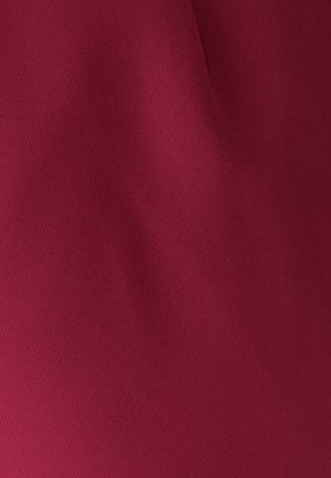 Tejido de textura suave en un profundo color burdeos con pliegues suaves y una iluminación suave.