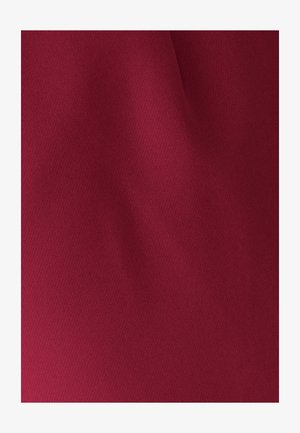 Tejido de textura suave en un profundo color burdeos con pliegues suaves y una iluminación suave.