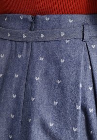 Denimkjol med midjeband och dragkedjestängning, ljusblått tyg prytt med små vita hjärtan, och en subtil texturfinish.