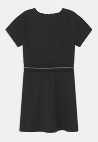 Czarna sukienka z krótkimi rękawami raglanowymi, okrągłym dekoltem i wyraźnym paskiem w talii z metalicznym wykończeniem. Gładki materiał, spódnica do kolan.