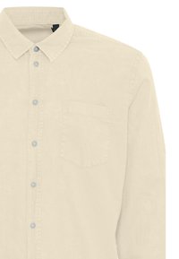 Beige Langarm-Hemd mit Knopfverschluss und Kragen, linker Brusttasche und sechs sichtbaren Knöpfen auf der Vorderseite.