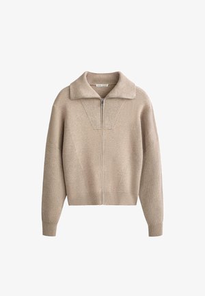 Beige striktrøje med lynlås foran, bred krave og ribbet tekstur. Har lange ærmer og en cropped nederste kant.