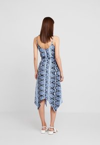 Blue snake print dress with spaghetti straps, fitted waist, and an asymmetrical hemline. The fabric has a smooth texture.