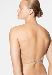 Beige beha met dunne bandjes, met een kruisdesign aan de achterkant en een haaksluiting, minimalistisch en gemaakt van zachte stof.