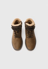 Een paar bruine leren veterschoenen met warme beige fleece voering, van bovenaf bekeken op een effen witte achtergrond.