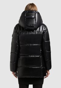 Zwarte pufferjack met een glanzende afwerking, verticale gestikte patroon, grote capuchon en logo-detail op de rug. De zoom eindigt boven kniehoogte.