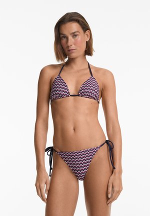Bikini set obsahující trojúhelníkový top a nastavitelné spodní díly se zavazováním na stranách. Tkanina má cik-cak vzor v purpurové, růžové a námořnické modré barvě.