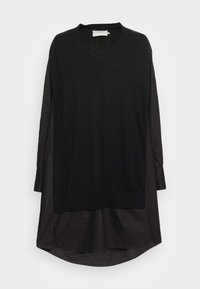 Schwarzes Langarmkleid mit V-Ausschnitt, gestricktem Oberteil und glattem, glänzendem unteren Abschnitt mit abgerundetem Saum.