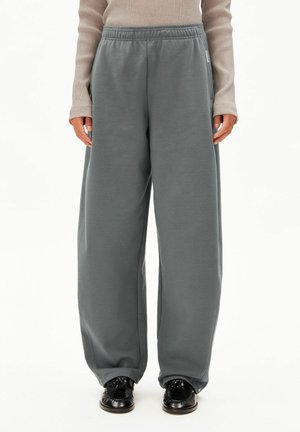 Grijze joggingbroek van zacht stof, met een comfortabele pasvorm, elastische tailleband en zijzakken, gecombineerd met zwarte schoenen.