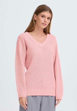 Różowy sweter robiony na drutach z v-dekoltem, luźnym krojem i ściągaczami. Tekstura jest miękka, z oddychającym splotem i swobodną sylwetką.