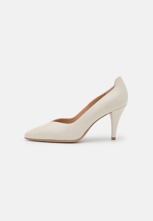Zapato de tacón alto de cuero blanco con puntera afilada, silueta estilizada y tacón delgado. Textura suave con un diseño minimalista.
