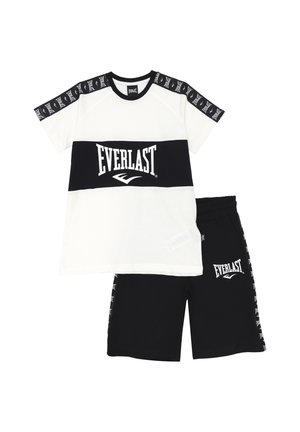 Completo sportivo in bianco e nero composto da una maglietta a maniche corte con un logo audace e pantaloni corti abbinati, entrambi realizzati in tessuto morbido.