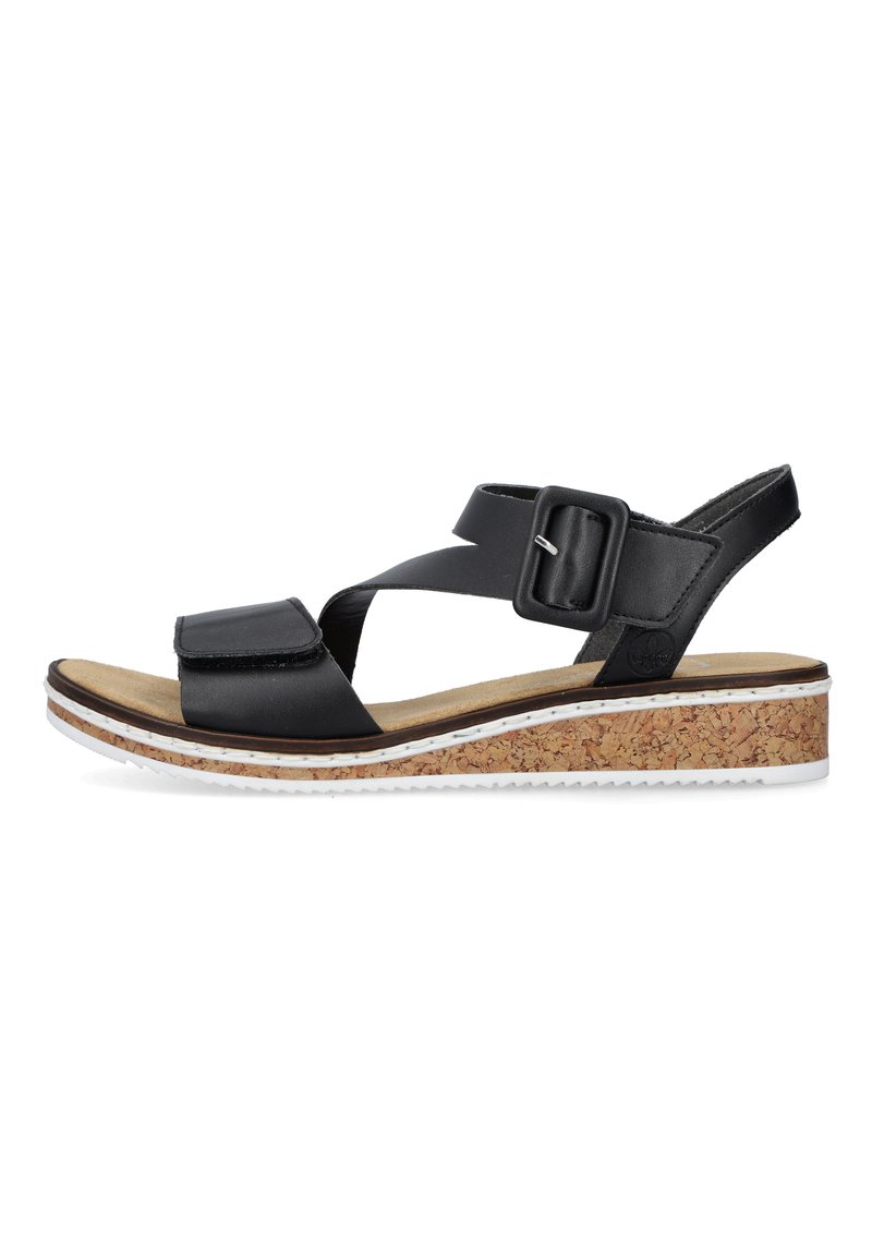 Black leather sandals with cross-strap design, adjustable buckle, cork wedge sole, and tan insole, featuring a textured white rubber outsole.