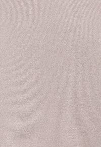 Ljust rosa stickat tyg med en slät, texturerad yta, som har ett jämnt ribbat mönster genom hela materialet.